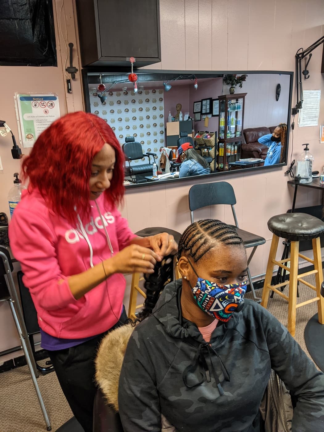 Student braiding knotless cornrows on a live client